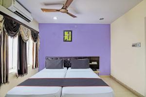 1 dormitorio con 1 cama grande y pared morada en OYO Flagship Hotel Night Owl, en Durgāpur