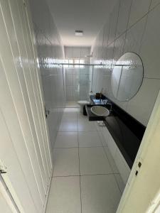 a white bathroom with a sink and a mirror at Pousada e Restaurante Mar dos Sonhos in Paripueira