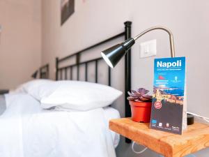 1 dormitorio con 1 cama y 1 mesa con lámpara en Ostello Bello Napoli, en Nápoles