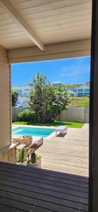 une terrasse avec bancs et une piscine dans une maison dans l'établissement Dune Rose Yzerfontein Villa, à Yzerfontein