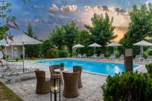 a pool with chairs and tables and umbrellas at Olga Rooms in Kanali