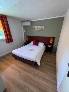 um quarto com uma cama grande com lençóis brancos e almofadas vermelhas em Initial by Balladins Lyon Villefranche-sur-Saône em Villefranche-sur-Saône