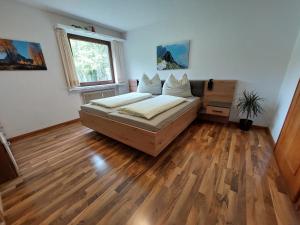 1 dormitorio con 1 cama y suelo de madera en Ferienwohnung Tschengla mit eigener Sonnenterrasse - Wiese - Wlan - Netflix, en Bürserberg