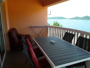 einen Tisch und Stühle auf einem Balkon mit Blick auf das Wasser in der Unterkunft Apartmani Zoran in Drage