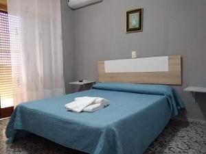 a bedroom with a blue bed with two towels on it at Habitaciones de Hostal a Primera linea de playa en Cullera in Cullera