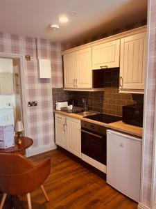 a kitchen with white cabinets and a sink and a stove at Red Cliff Lodge in Spanish Point