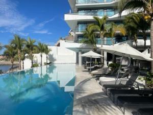 a swimming pool with chairs and umbrellas next to a building at Fantastic designer apartment, beachfront! in Bucerías