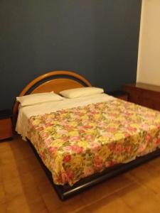 a bedroom with a bed with a floral blanket at Appartamento 300m dal mare AMANTEA CALABRIA in Amantea