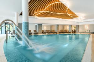 a swimming pool in a hotel lobby with a ceiling at Kenese Bay Garden Resort & Conference in Balatonkenese
