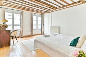 um quarto com uma cama, uma secretária e janelas em Appartement Quartier Saint-Germain em Paris