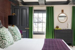 um quarto com cortinas verdes, uma cama e uma janela em The Merchant em Salem