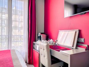 um quarto cor-de-rosa com uma secretária e um espelho em Best Western Nouvel Orléans Montparnasse em Paris