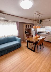 a living room with a table and a blue couch at HYGGE HOUSE 旅人の家 丸ごと貸切 JR線 常磐線北柏駅徒歩2分 キッチン調理器具 生活必需品付 高速WiFi 駐車無料上野駅まで30分 in Kashiwa
