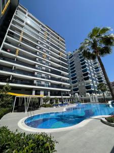 a large apartment building with a swimming pool and palm trees at SA Apartments! 1bd Flat 300m to the Beach in Alanya