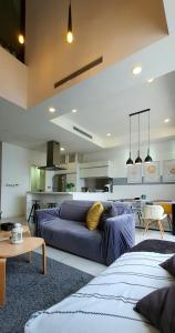 a living room with a blue couch and a kitchen at MCity Ampang (Room in shared apartment) in Kuala Lumpur