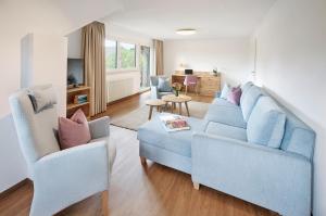 a living room with a blue couch and two chairs at Hotel Gasthof Engel in Appenweier