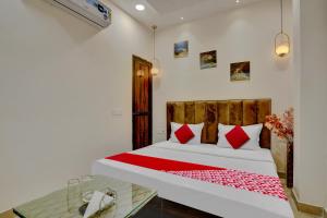 a bedroom with a bed with red pillows and a glass table at Flagship Hotel Orchid in Ludhiana
