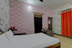Schlafzimmer mit einem weißen Bett und rosafarbenen Tapeten in der Unterkunft OYO The Home in Lucknow