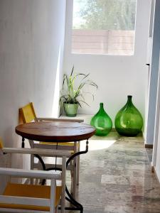 una mesa y sillas en una habitación con jarrones verdes en Kalimera Studios and Apartments en Moraitika