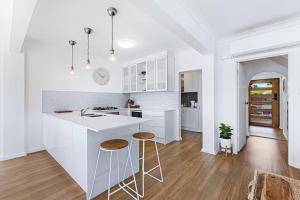 a white kitchen with a counter and stools in it at Lakeside Mews in Grange +13 photos