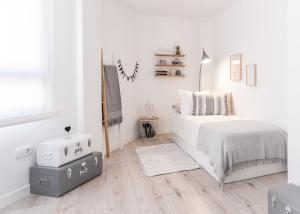 biała sypialnia z łóżkiem i drewnianą podłogą w obiekcie Ático Chic San Jorge w Murcji