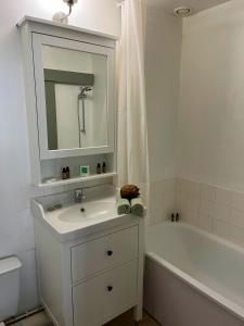 een witte badkamer met een wastafel en een bad bij Élégant Studio en Hypercentre dans le Quartier Historique Animé avec Parking Gratuit in Caen