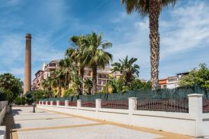 a long white fence with palm trees and buildings at Apartamento Sugar Factory in Torre del Mar