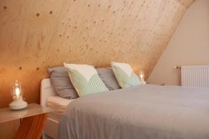 a bed and a chair in a room with wooden walls at B&B Wasboerderij Beek Ubbergen in Beek