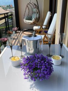 a table with purple flowers and glasses on a balcony at La Rosa del Lago in Lenno