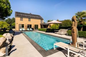 a swimming pool in a yard with a house at LA VILLA DE SENY , villa de charme avec jardin ,Piscine nature, jacuzzi , petanque, fitness, billard,ping pong, in Seny