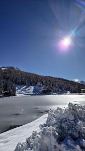 un lac enneigé avec le soleil dans le ciel dans l'établissement Casa Caliman, à Santa Caterina