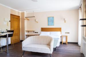 a bedroom with a white bed and a chair at Apartamentos San Jorge in Nueva de Llanes