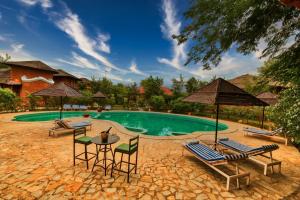 a swimming pool with chairs and tables and umbrellas at The Earth at Ranthambore in Sawāi Mādhopur