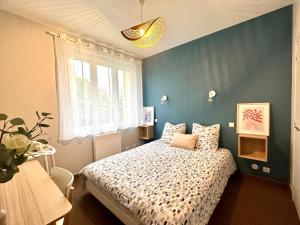 a bedroom with a bed and a blue wall at Le Cabieu in Ouistreham