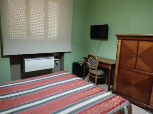 塔蘭托的住宿－廣場酒店，一间卧室配有一张床、一台电视和一张书桌