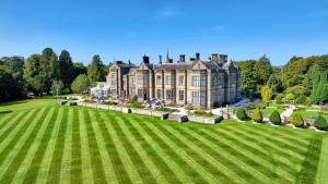 a large house with a large lawn in front of it at Matfen Hall Hotel, Golf & Spa in Matfen