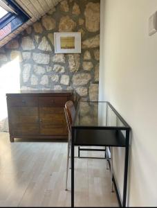 einen Glastisch und einen Stuhl in einem Zimmer mit einer Steinmauer in der Unterkunft Room's near Belval university in Esch-sur-Alzette