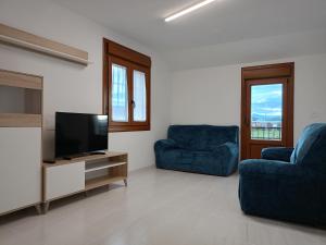 uma sala de estar com 2 cadeiras azuis e uma televisão de ecrã plano em Casa Eloy em Barreiros
