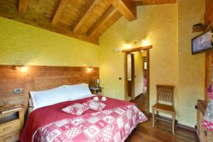 een slaapkamer met een groot bed en een rood dekbed bij Hotel Le Petit Abri in Champoluc