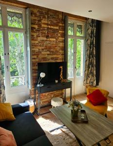 uma sala de estar com um sofá e uma parede de tijolos em Studio Luxine - 2 personnes - Vue sur le Canal du Midi em Toulouse