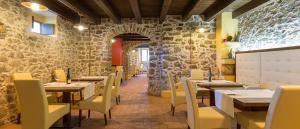 um restaurante com mesas e cadeiras e uma parede de pedra em Hotel Palazzo Costa em Beverino