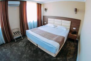 una camera con un grande letto in una camera d'albergo di Osh Grand Hotel Chavo a Oš