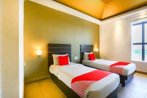 duas camas num quarto de hotel com almofadas vermelhas em Super Collection O Skywalk Hotel em Chennai