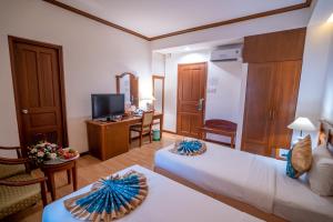 una camera d'albergo con letto, scrivania e TV di Oscar Saigon Hotel ad Ho Chi Minh