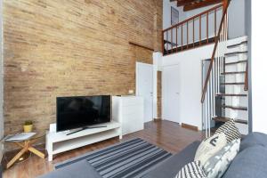 a living room with a large television and a brick wall at GuestReady - Mezzanine comfort in Valencia in Valencia