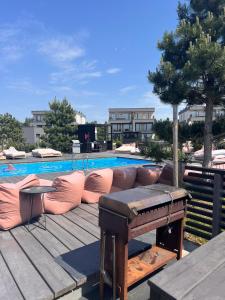 an outdoor deck with a couch and a piano next to a pool at Katrina - Kunigiškių apartamentai - Mano Jūra 2 in Palanga