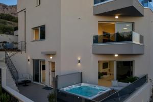 a house with a hot tub on a balcony at Luxury Apartments Podgora in Podgora