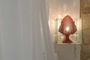 una lámpara sentada en un estante junto a una cortina en Le Nicchie luxury rooms, en Lecce