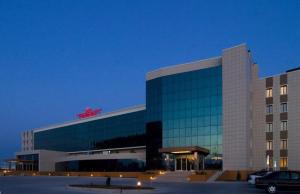 ein großes Gebäude mit einem davor geparkt in der Unterkunft Grand Nur Plaza Hotel in Aqtau