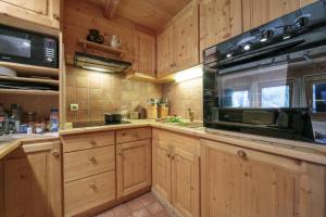 a kitchen with wooden cabinets and a microwave at Chalet Du Croz 1er - Happy Rentals in Chamonix